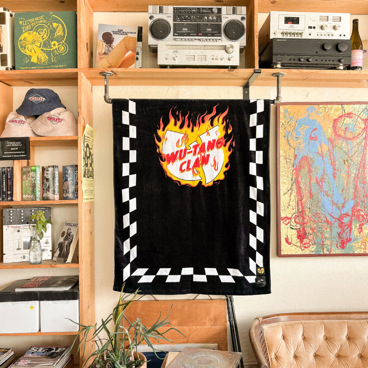 Towel with graphic print hanging indoors, displayed near shelves and stereo equipment.