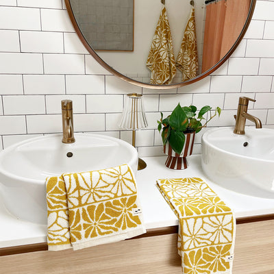 Cotton floral hand towels 550 GSM on double sink vanity with gold faucets.
