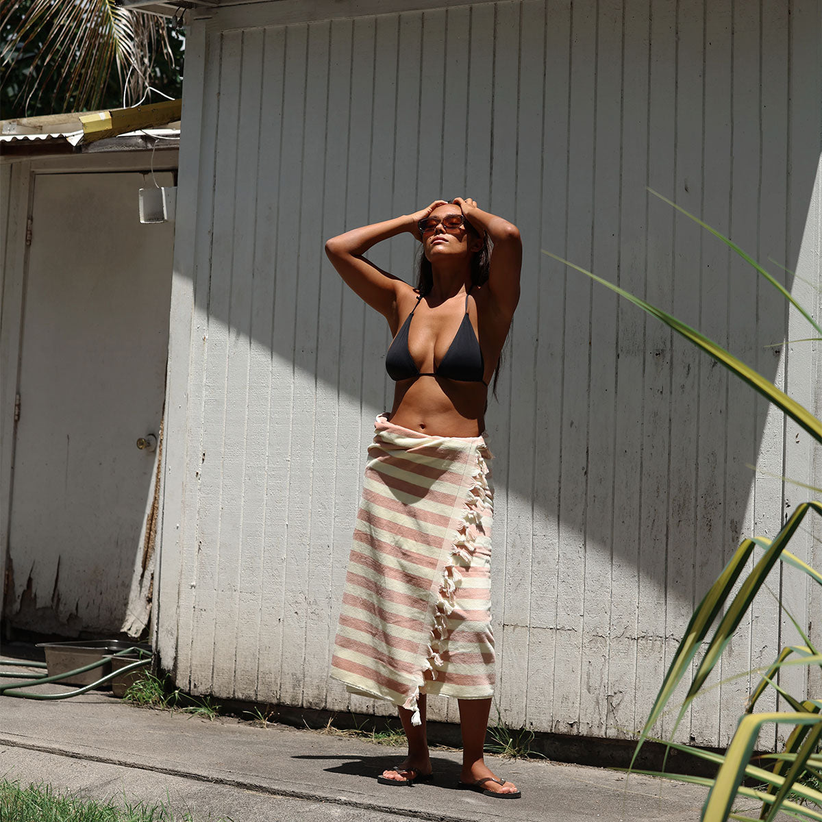 Bikini top and striped skirt with tassel fringe in natural sunlight.