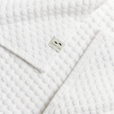 Spa towel, white textured cotton with sustainable material tag.