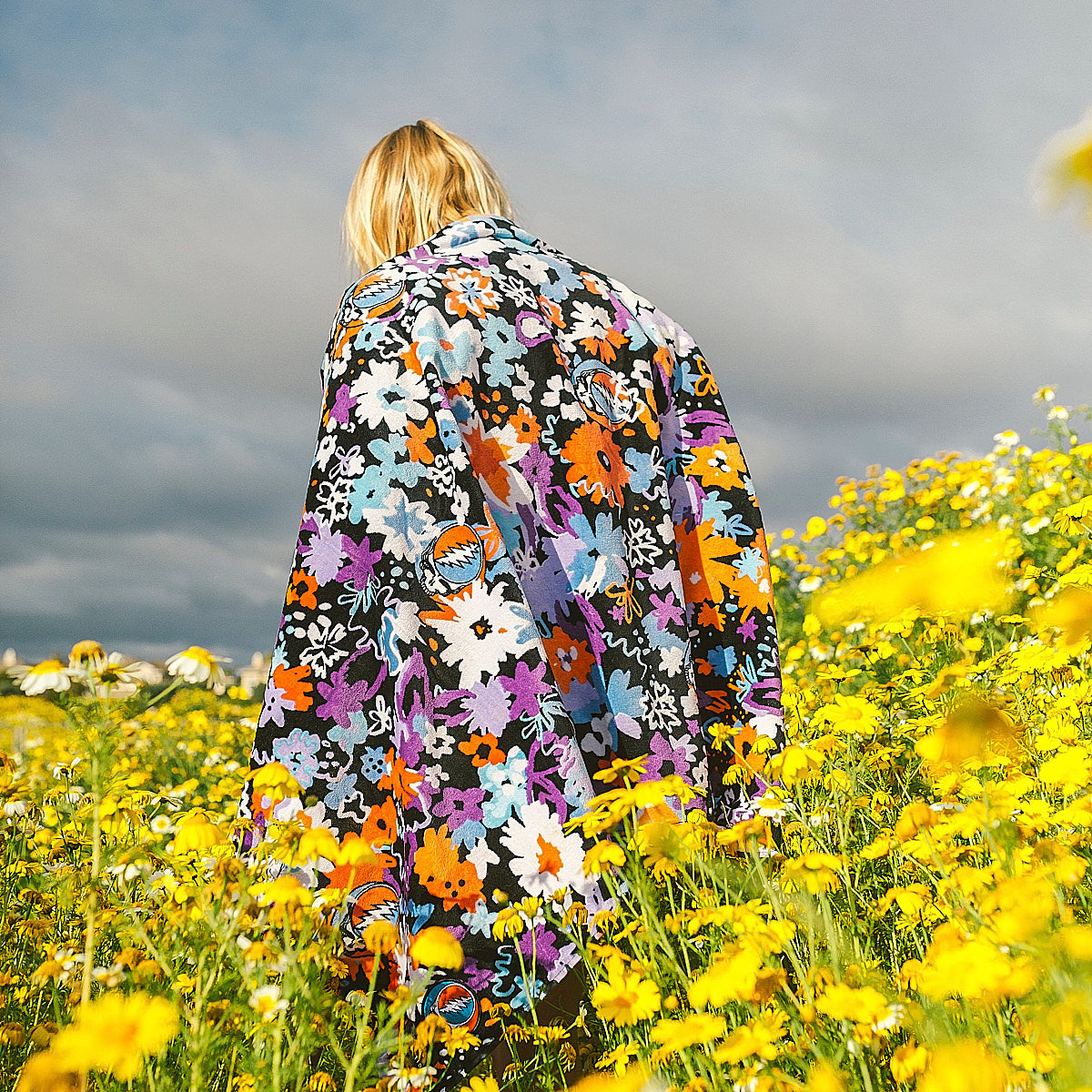 Floral cotton towel with colorful pattern in a field of yellow flowers.