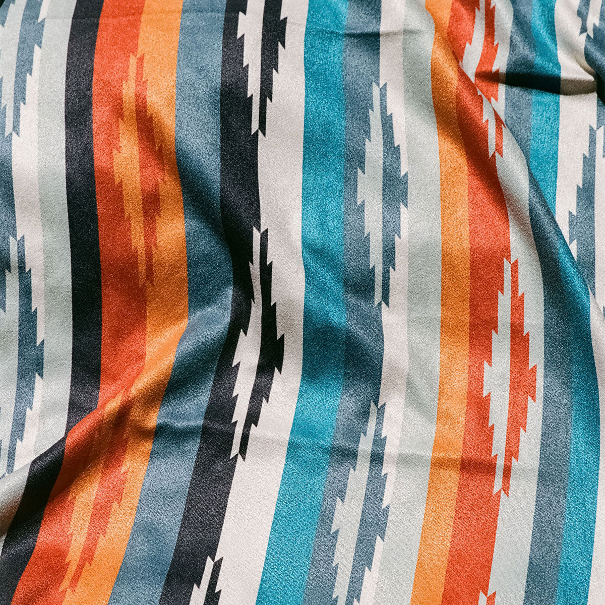 Oversized quick-dry towel with orange, blue, and black zigzag geometric pattern.