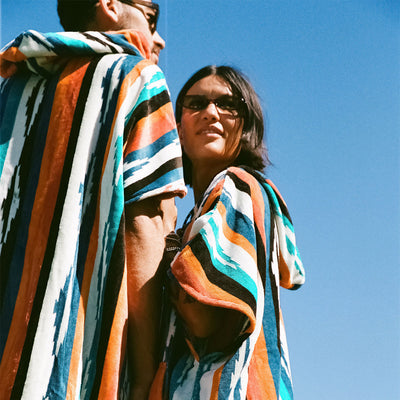 Cotton terry towel ponchos with colorful stripes and sunglasses.
