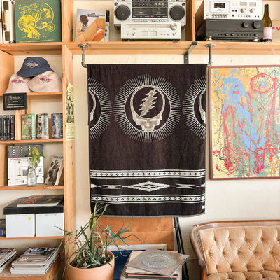 Plush towel with plant, displayed on shelf in room with abstract art and colorful blanket.