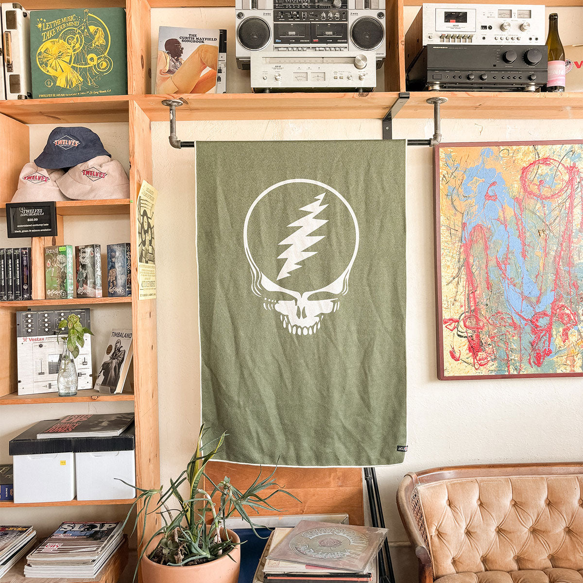 Olive quick-dry towel with skull logo on cozy furniture in music-themed room.