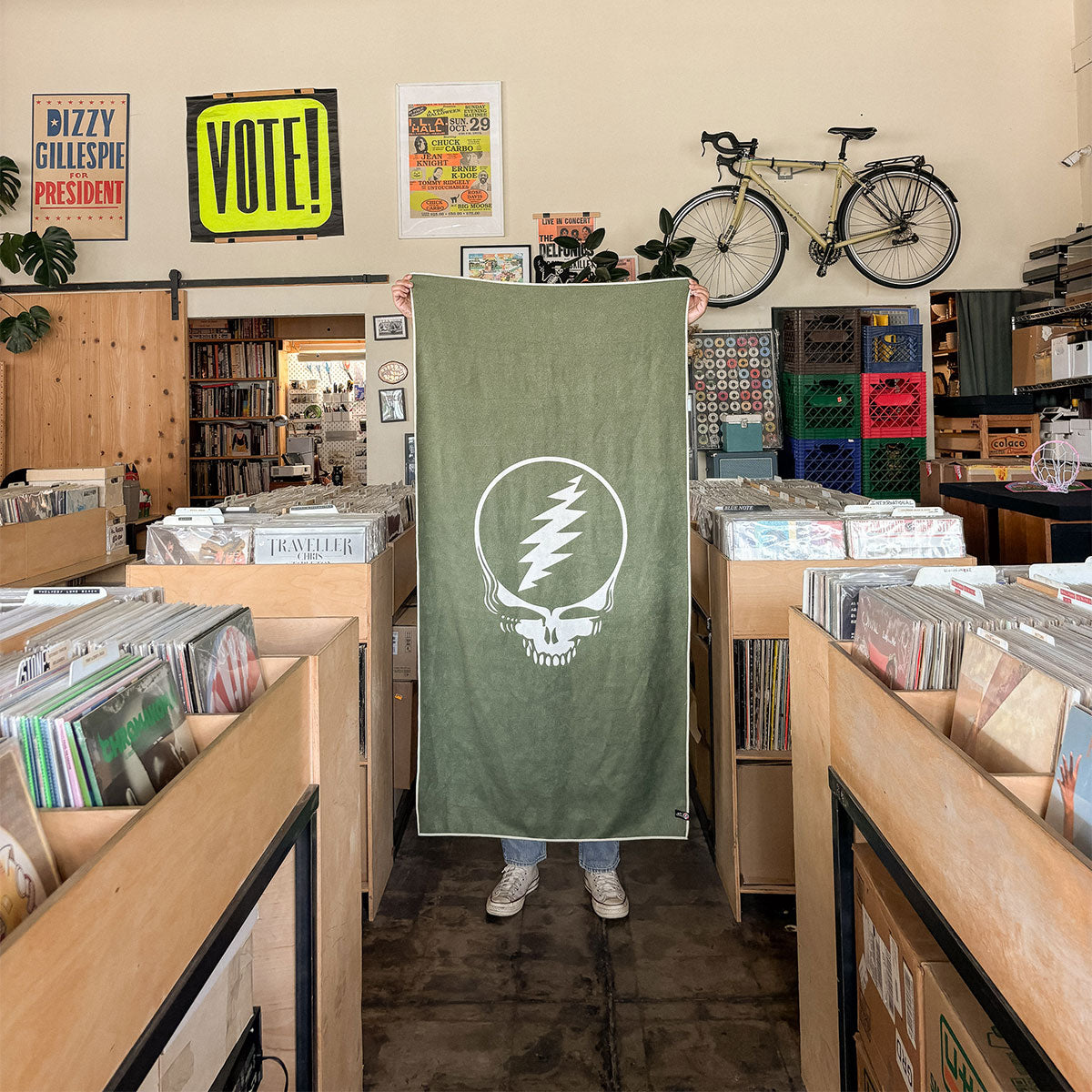 Green recycled quick-dry towel with skull and lightning logo in store setting.