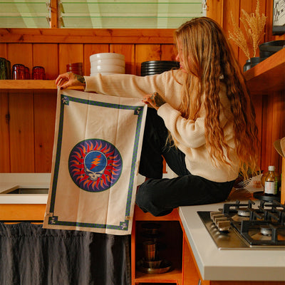 Sustainable cotton kitchen towel with blue and red skull and lightning bolt graphic.