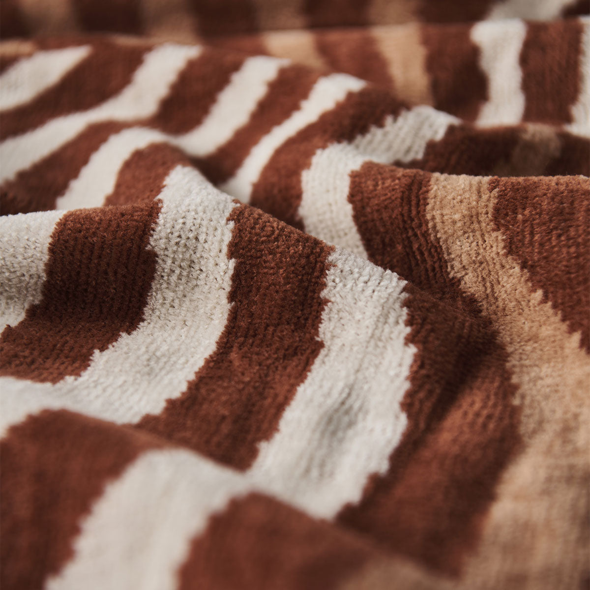 Textile fabric, textured, with retro wavy brown and cream stripe pattern, close-up view.