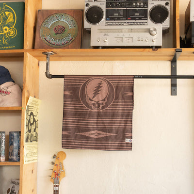 Brown recycled waffle kitchen towel with iconic skull logo hanging under a record shelf.