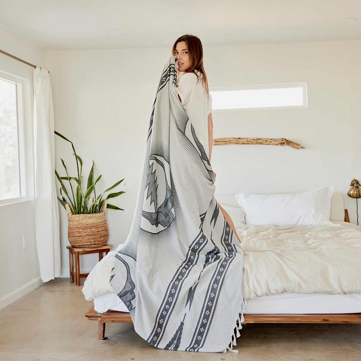 Picnic blanket, lightweight fabric with colorful design, shown in a minimal bedroom setting.