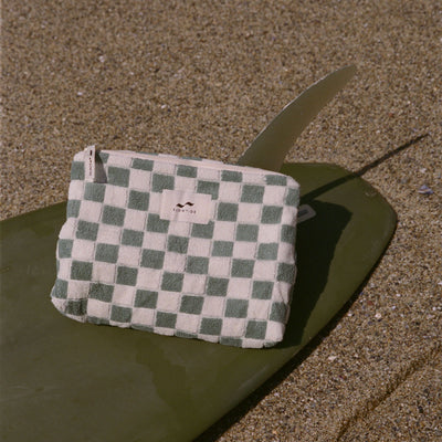 Cotton canvas pouch in green and white on surfboard at beach.