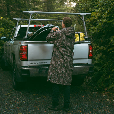 Camo all-weather jacket with rugged pattern outdoors near a silver pickup truck.