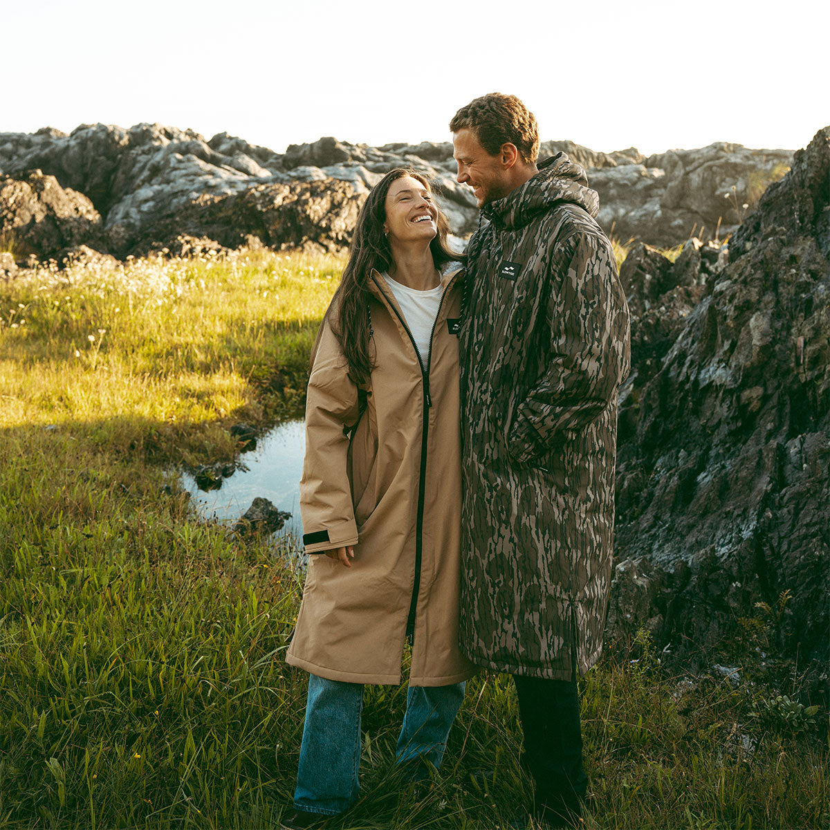 Long waterproof parka coat with hood, outdoor setting.