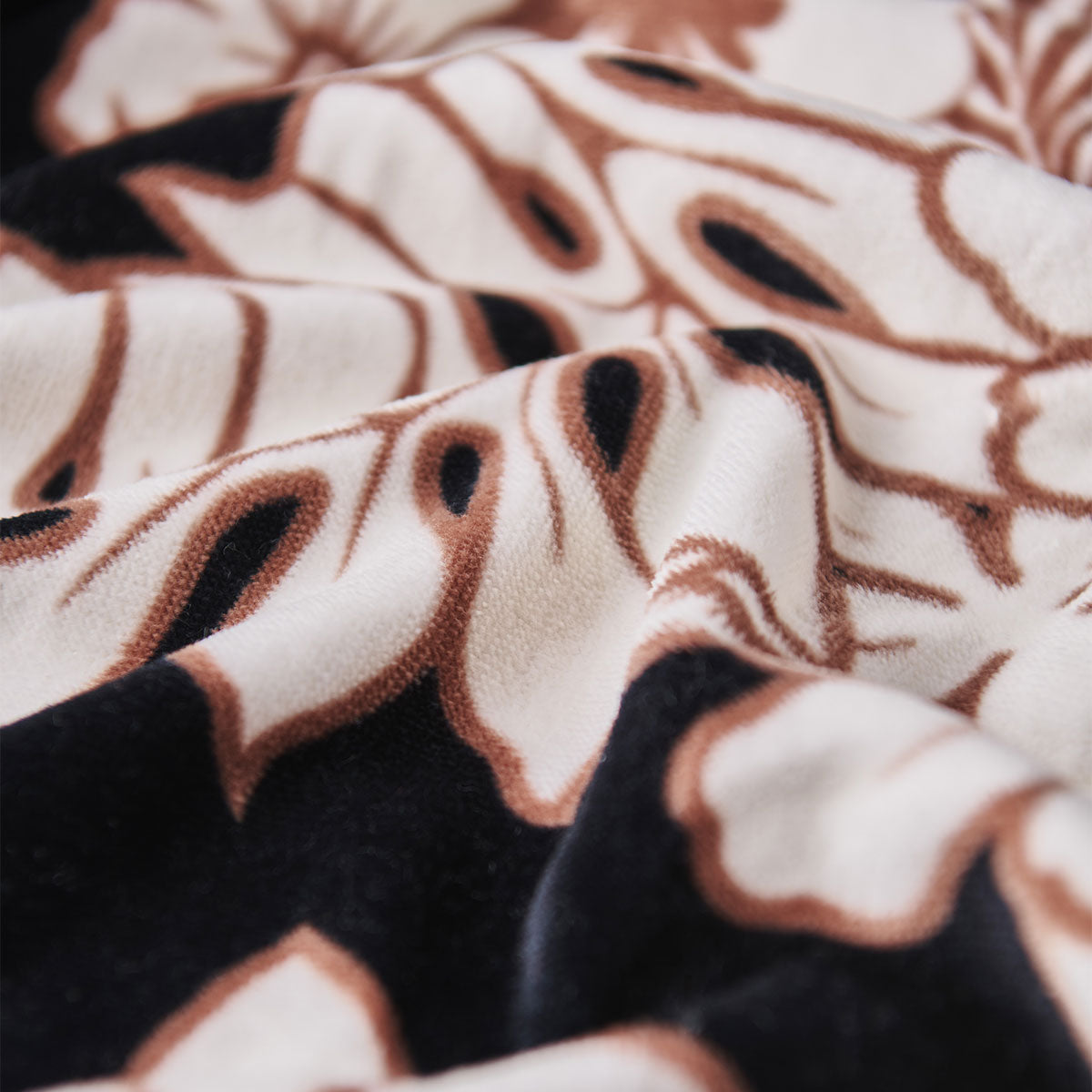 Velour towel with black and white floral pattern on cream background.