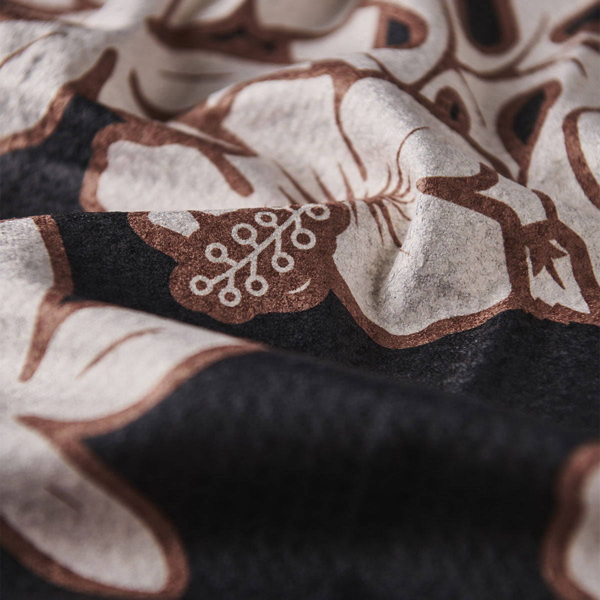 Quick dry towel, black fabric with brown and white floral pattern, soft texture.