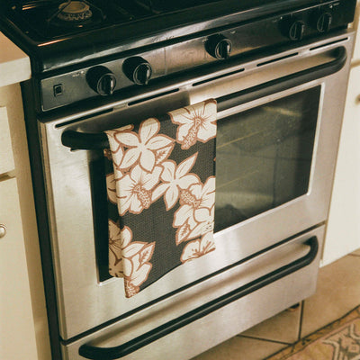 Quick dry towel with floral pattern hanging on stainless steel oven handle.