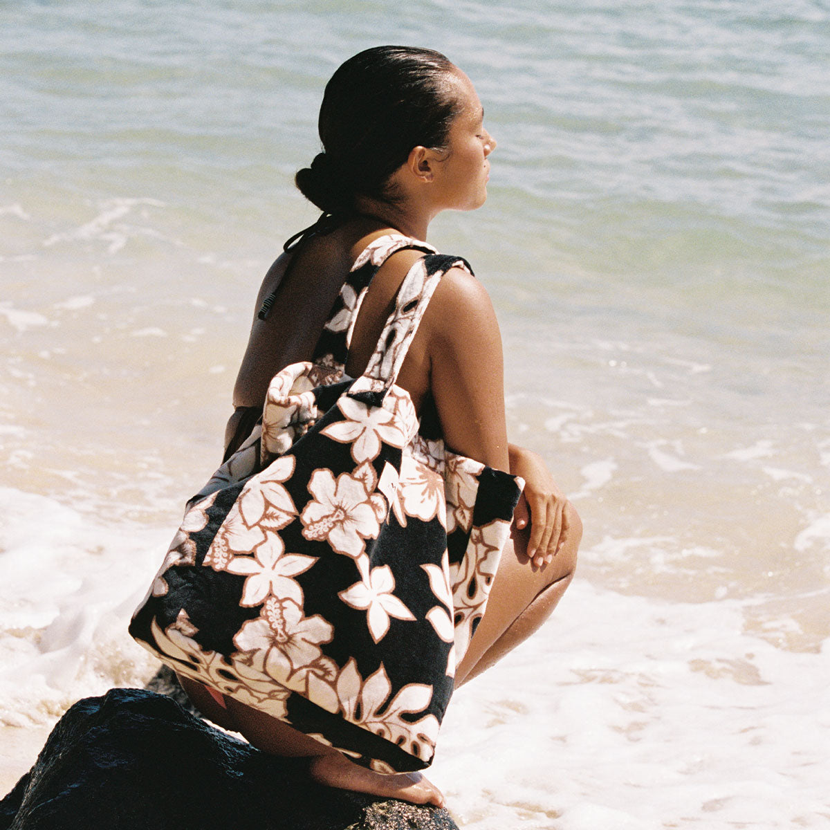 Floral beach bag with cotton canvas lining on a rock by the ocean.