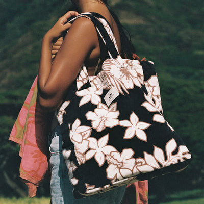 Black floral print tote bag, terry exterior, cotton lining, shown with pink towel draped over.