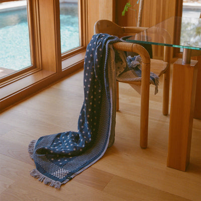 Lightweight blue scarf with pattern on wooden chair by window.