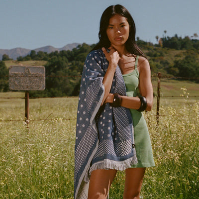 Green dress and blue patterned Turkish towel, lightweight and sand-resistant.