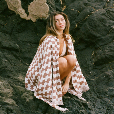 Turkish towel, cotton, checkered pattern, displayed on dark rocks.