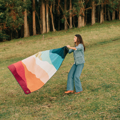 Outdoor blanket with colorful mountain landscape pattern.