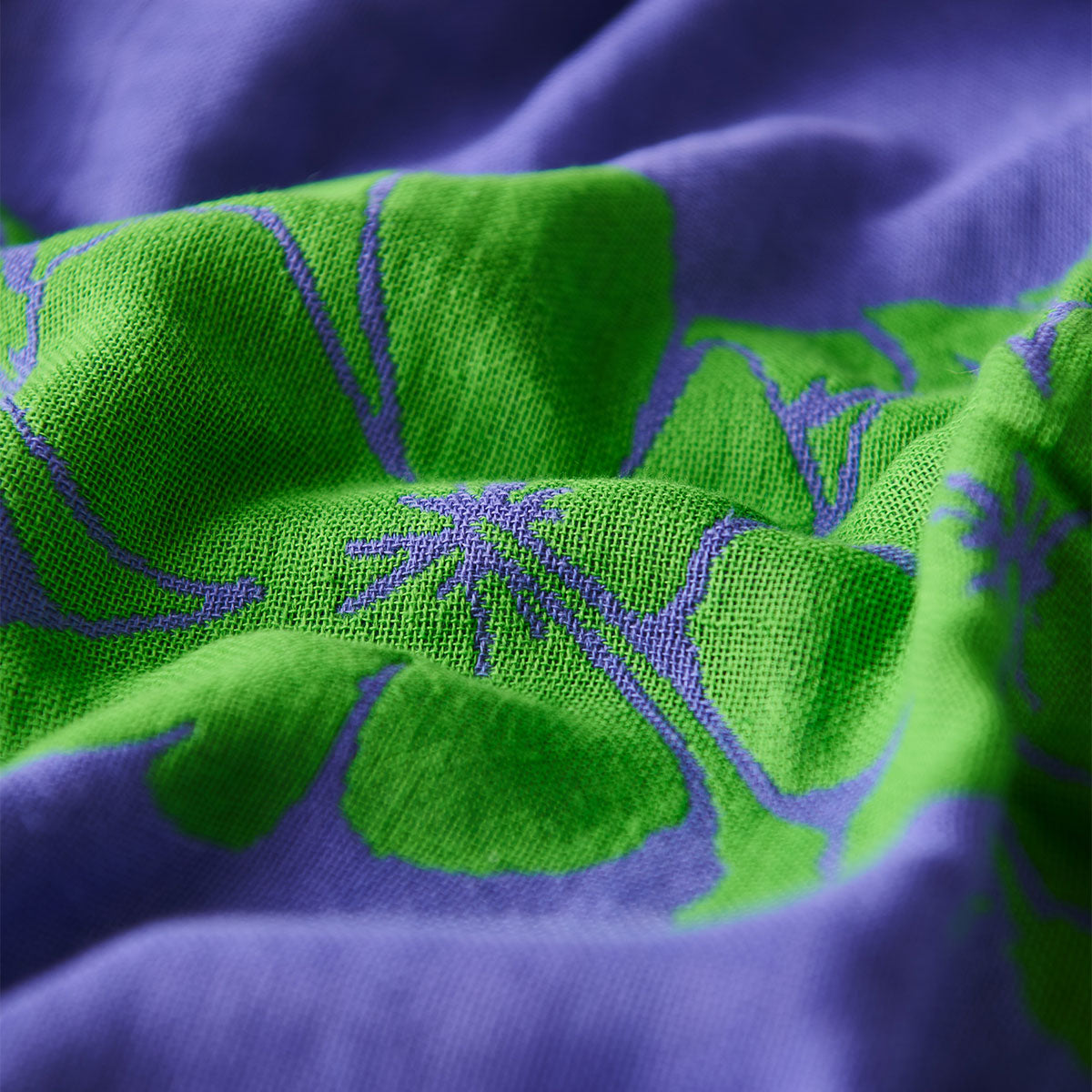 Beach towel, sand-resistant blue and green fabric with leafy pattern, close-up texture.