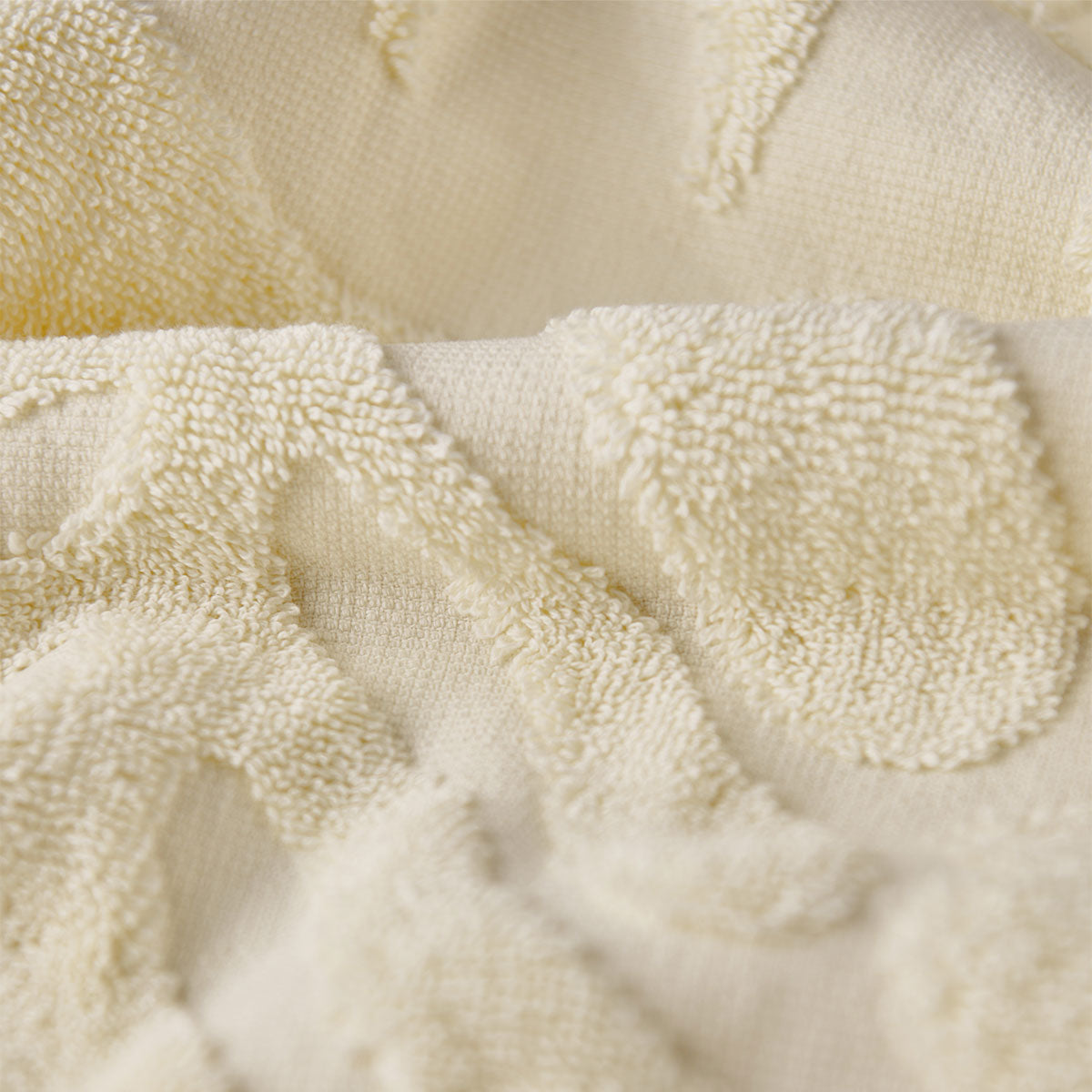 Cotton towels in cream with plush texture and raised loop pattern, close-up.