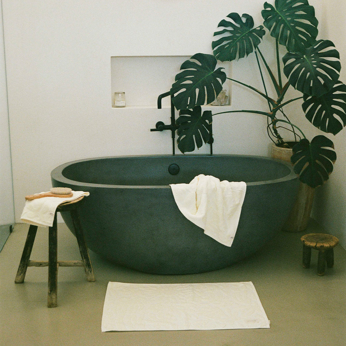 Oval bathtub with dark finish and plush cotton towels in a modern bathroom setting.