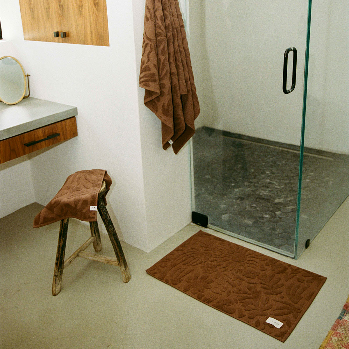 Bath mat and towel set in 1000 GSM cotton with a raised botanical pattern.