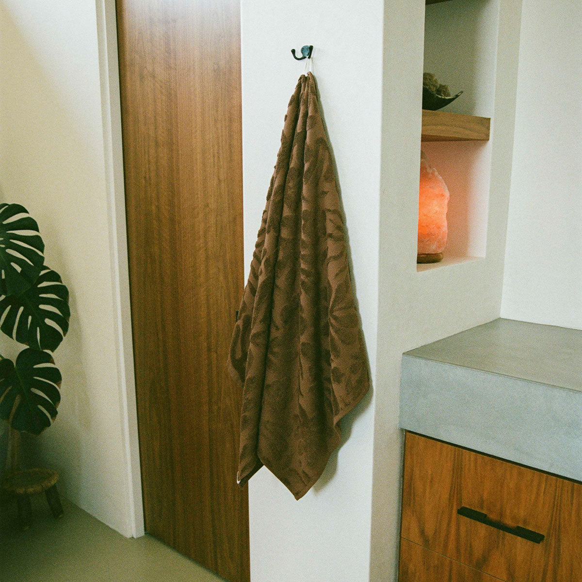 Plush bathroom towel with soft texture on wall hook in minimalist setting.
