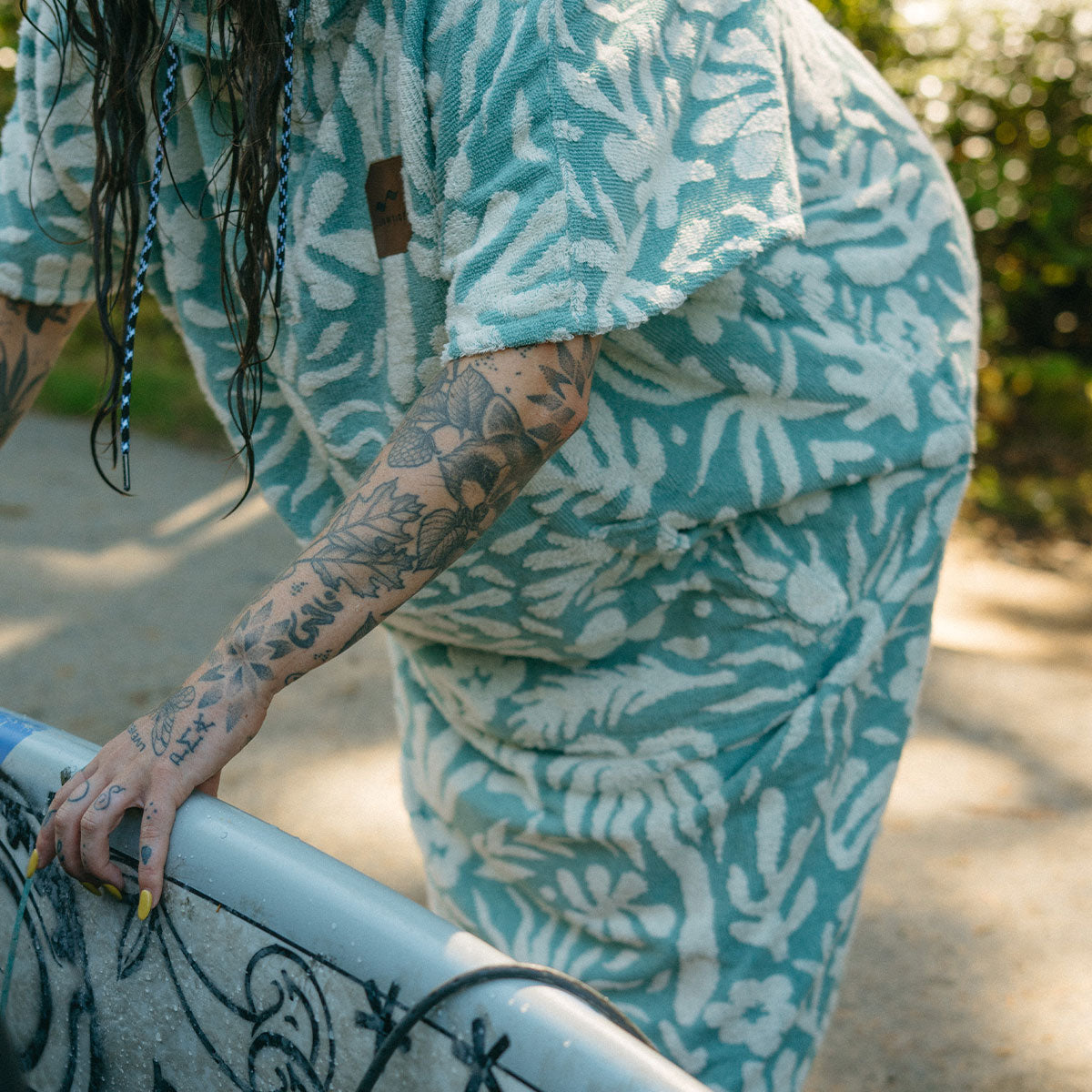 Blue cotton terry towel poncho with patterned design, outdoor surf context.