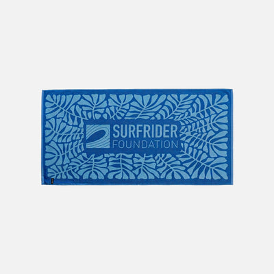 Blue cotton beach towel with wave logo, made from sustainable materials.