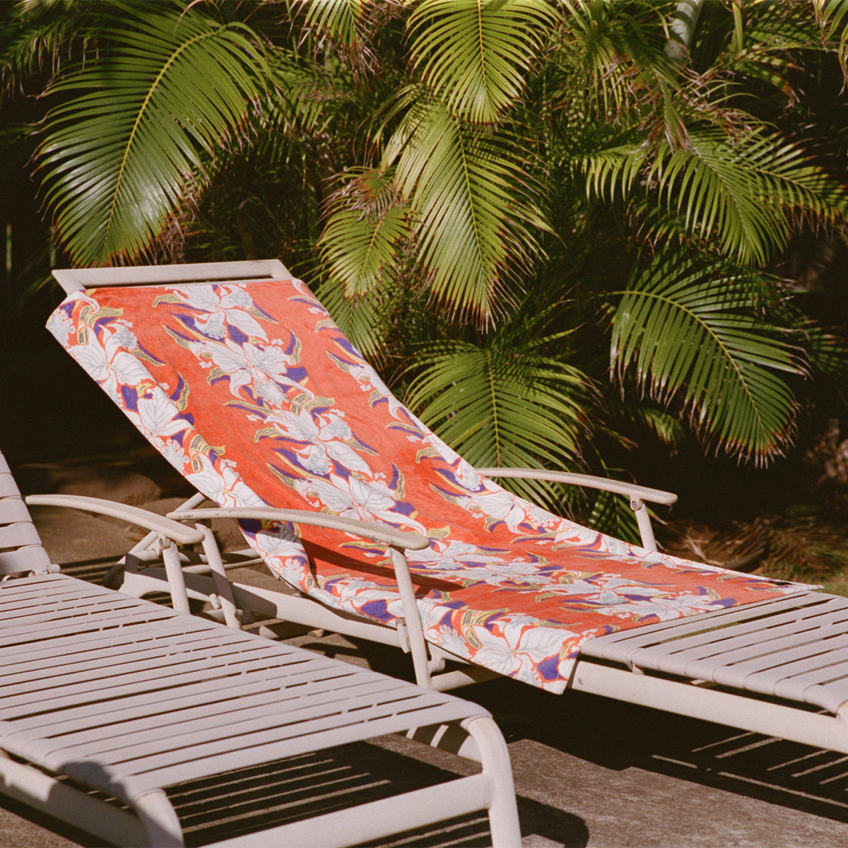 Velour towel with printed design on lounge chair outdoors.