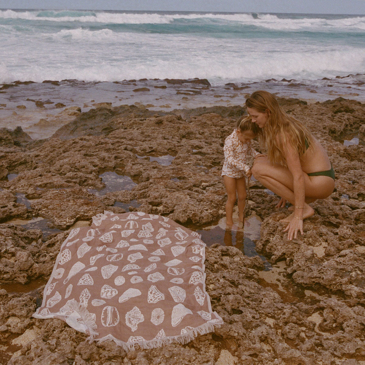 Quick-drying patterned towel on rocky shoreline.