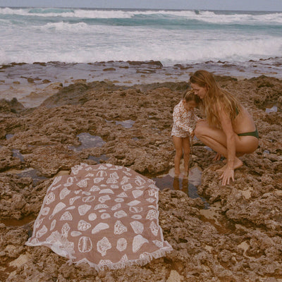 Quick-drying patterned towel on rocky shoreline.