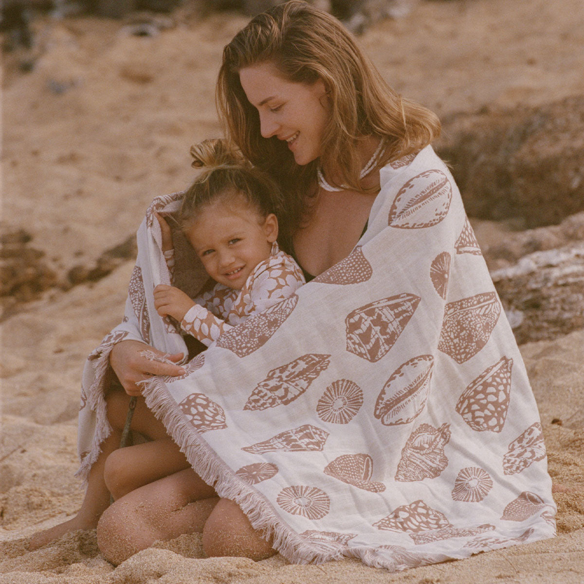 Patterned sand-resistant beach towel with child, shown on sand for scale and context.
