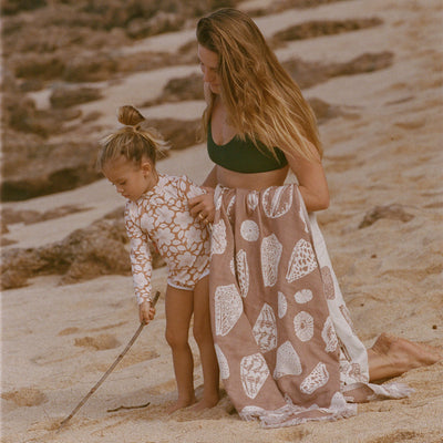 Sand-resistant towel with child-safe surface, shown in use on the beach.