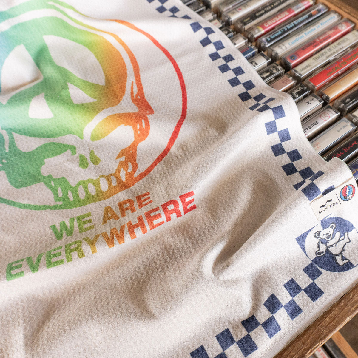 Kitchen towel with colorful skull and We Are Everywhere text, next to cassette tapes.