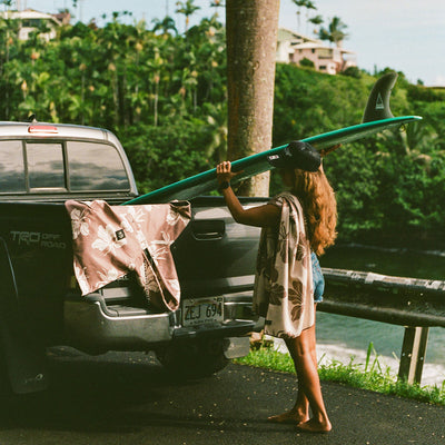 Recycled material quick-dry poncho in brown floral print on a truck tailgate with a surfboard.