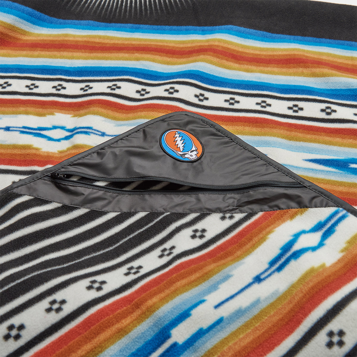 Outdoor blanket, recycled material, colorful stripes, pocket, skull logo patch.