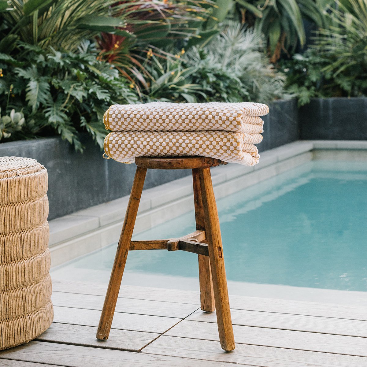 Cotton towels with absorbent texture on wooden stool by a pool.