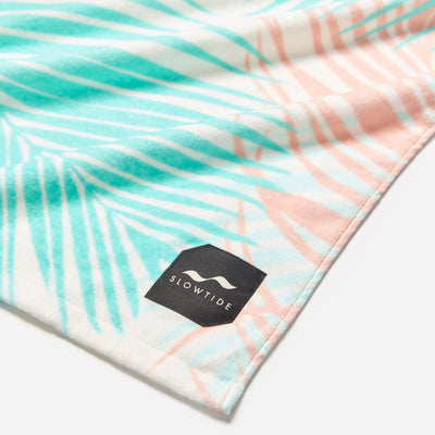 Cotton towel with pastel palm leaf pattern, absorbent, suitable for bath or beach use.