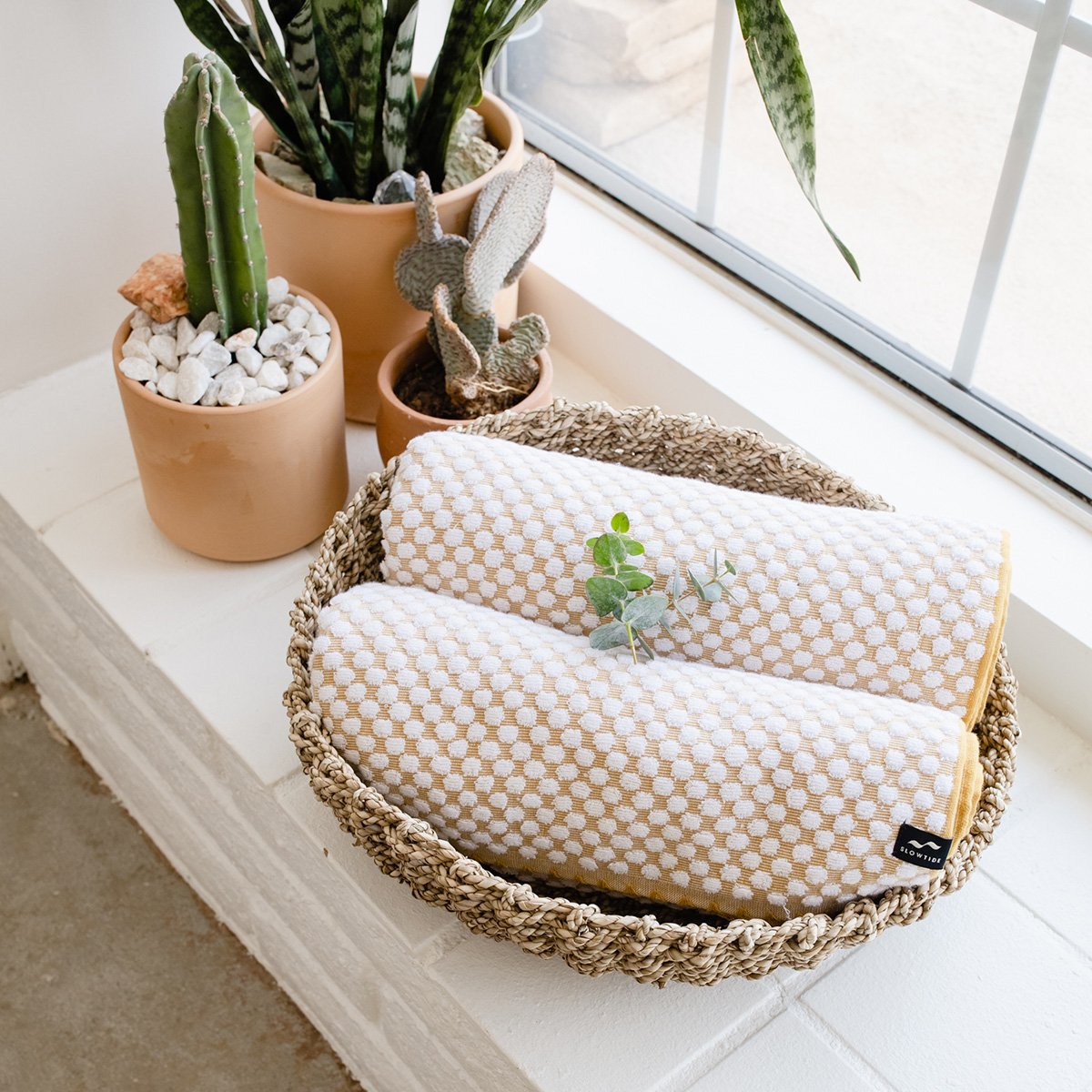 Cotton towels in a woven basket on a windowsill.
