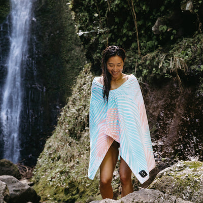 Printed velour towel with colorful pattern, shown outdoors near rocks and waterfall.