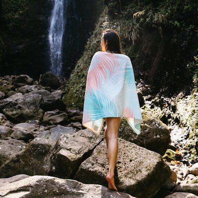 Printed velour towel with nature-inspired pattern, displayed outdoors by a waterfall and rocks.