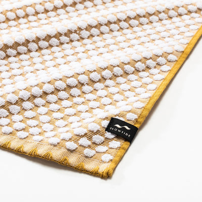 Cotton towel with yellow and white pattern, absorbent material, close-up view.