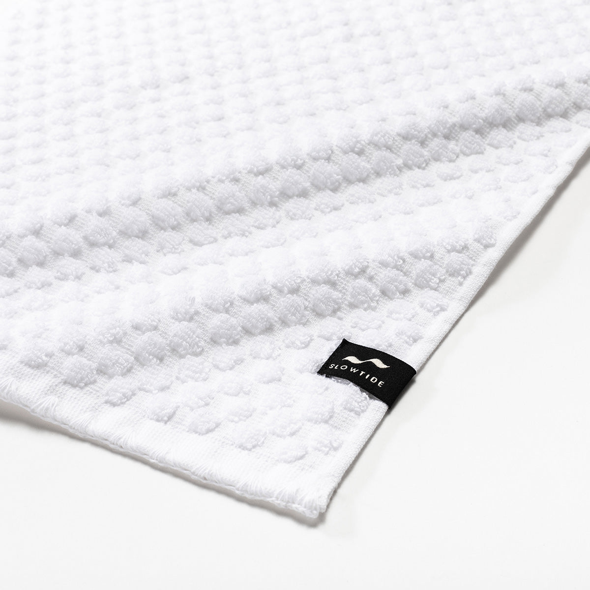 White textured spa towel, 500 GSM sustainably sourced cotton, small fabric tag.