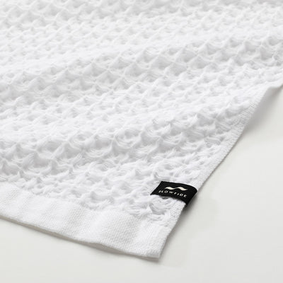 White waffle bath towel with small black tag in the corner.