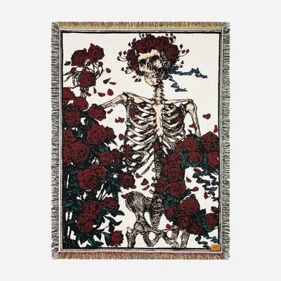 Fringed tapestry with woven skeleton and red roses design.